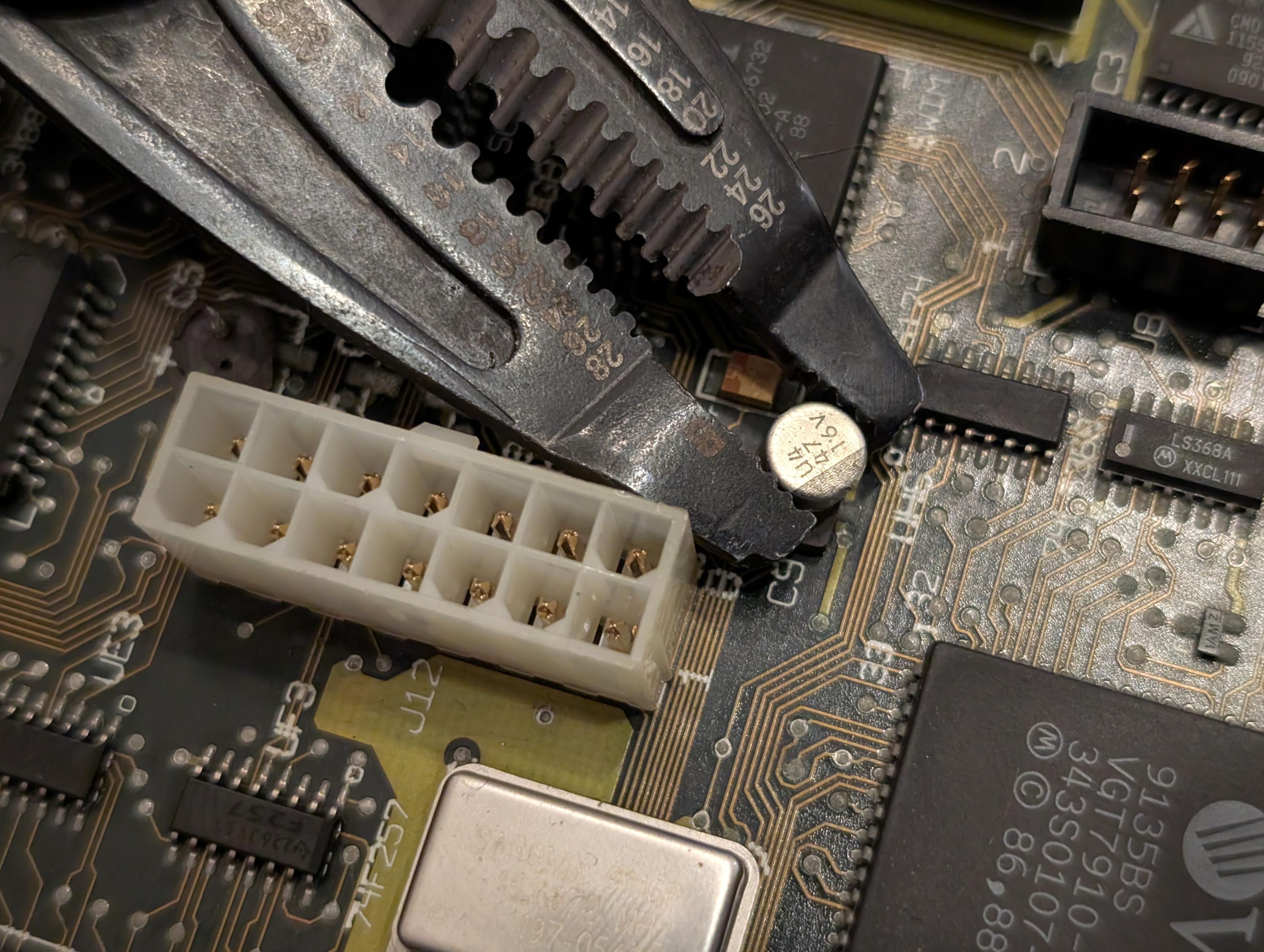 Closeup of pliers removing a capacitor