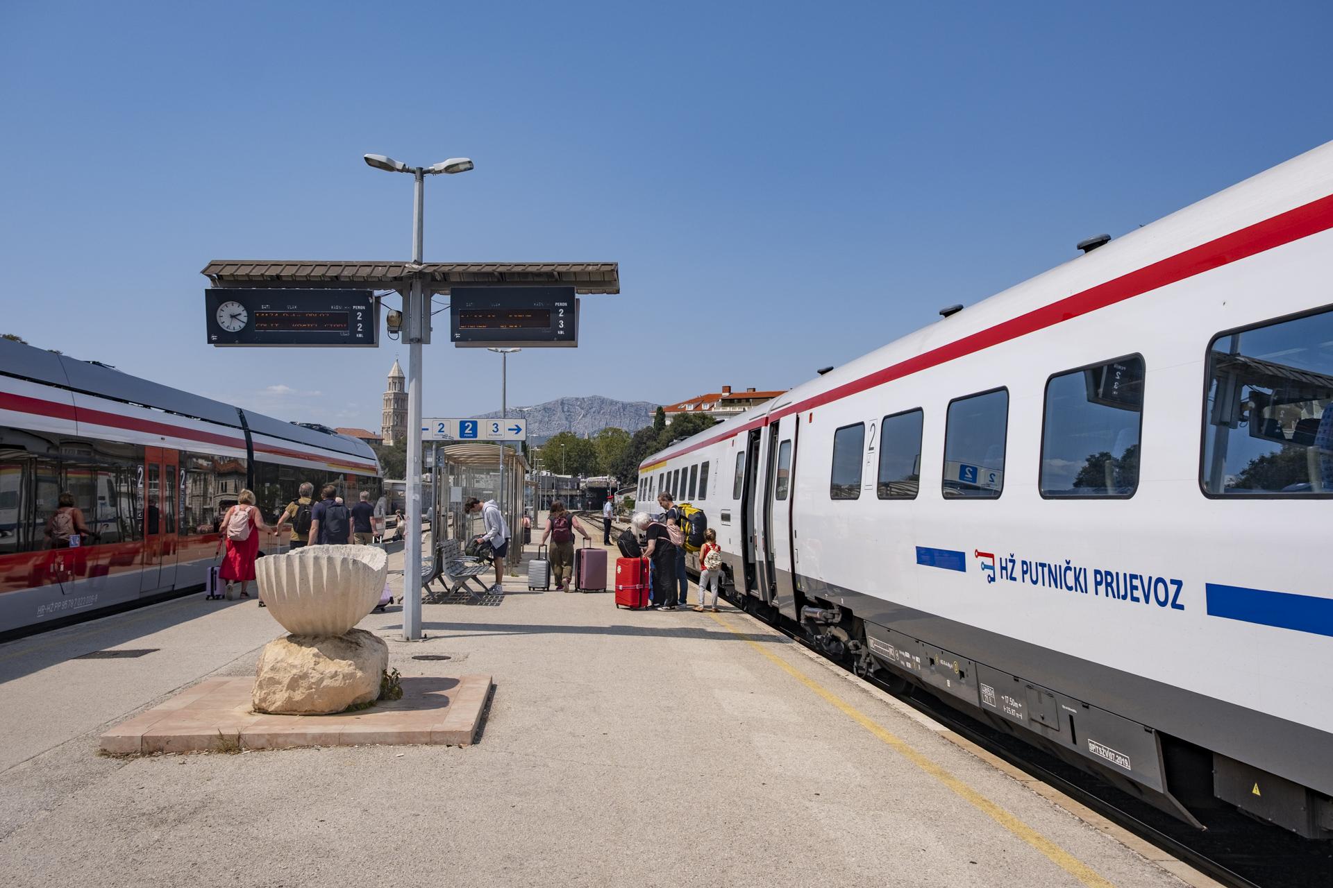 Two trains at a sunny uncovered platform
